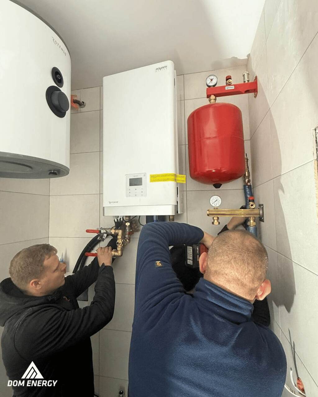 Dwóch techników podczas montażu hydraulicznego pompy ciepła Rotenso i naczynia przeponowego w Radomiu.