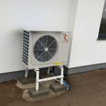Jednostka zewnętrzna pompy ciepła Rotenso Aquami 8 kW typu Split zamontowana na stojaku przy budynku w Radomiu.