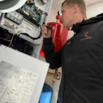 Instalator wykonuje podłączenia elektryczne wewnątrz jednostki pompy ciepła Rotenso Aquami 8 kW w Radomiu.